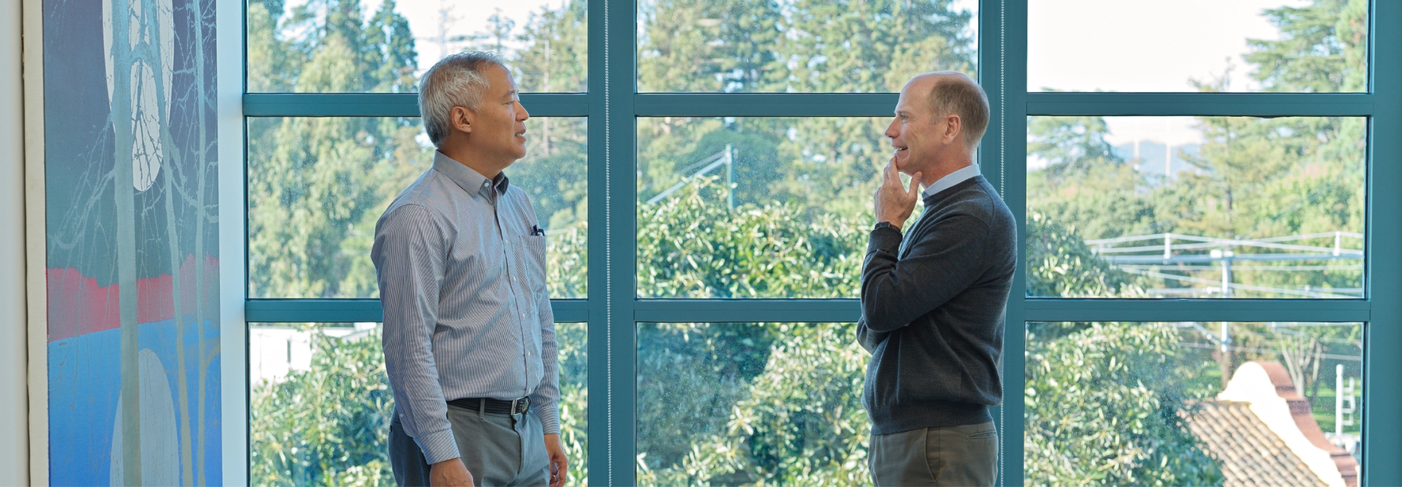 Fisher Lynch colleagues talk by a large window, sharing ideas in a relaxed office setting.