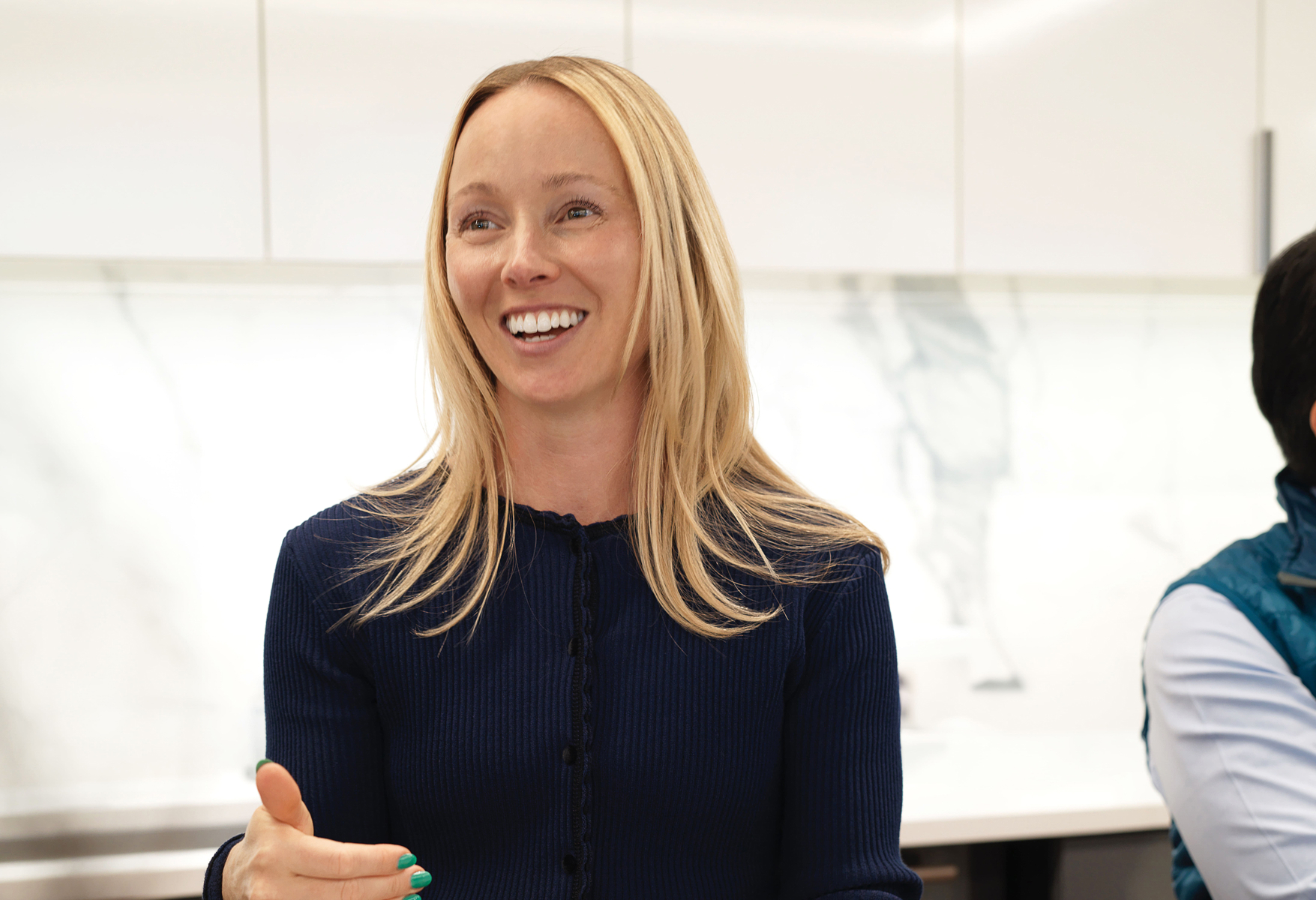 Smiling colleague speaking in a modern office break room.