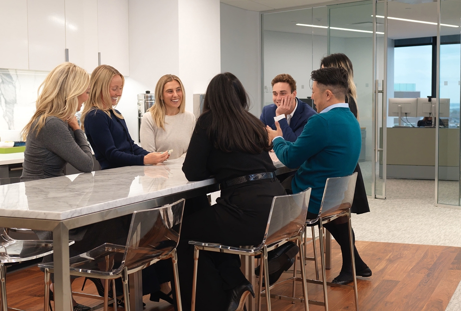 Colleagues chatting around a marble table in a modern office break room.